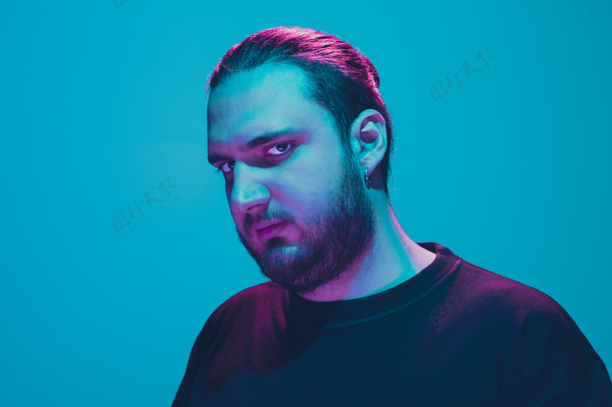 脸一个男人的肖像 蓝色的工作室背景 五颜六色的霓虹灯冷静严肃的男模特头霓虹灯胡须