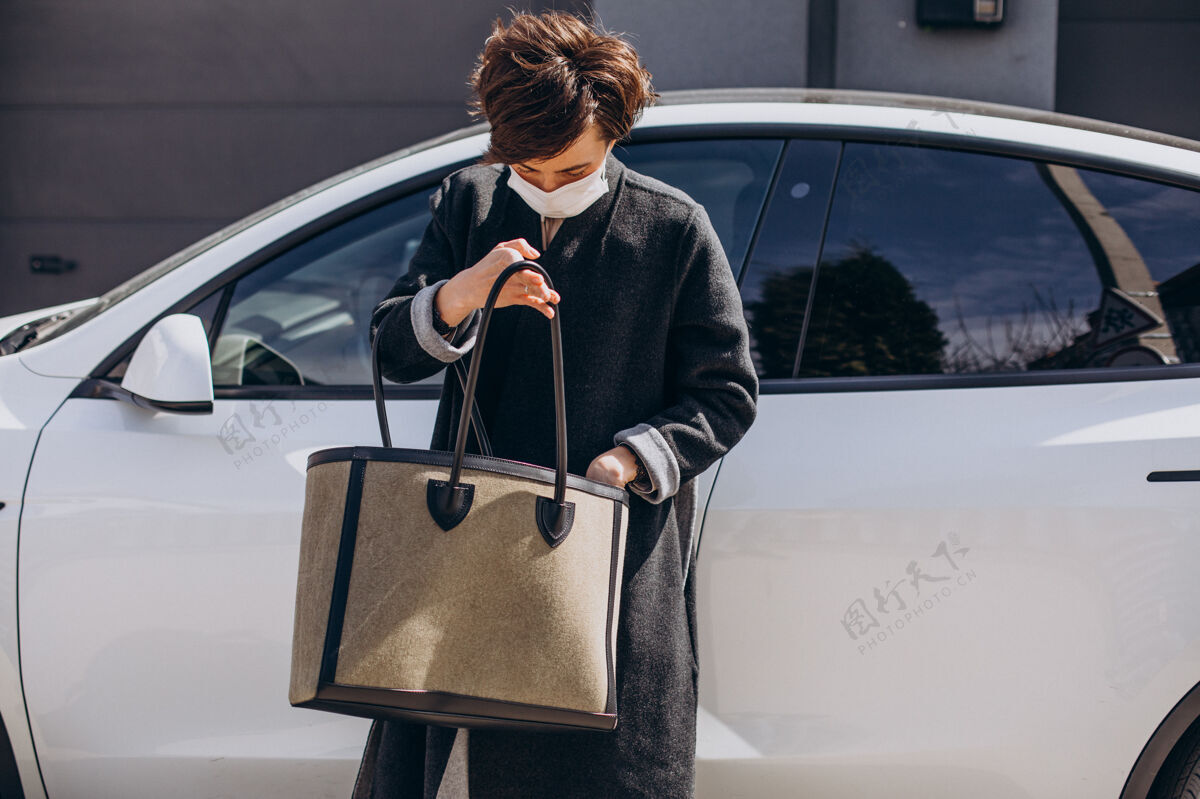 车辆戴着口罩的女人站在她的车旁边道路女人优雅