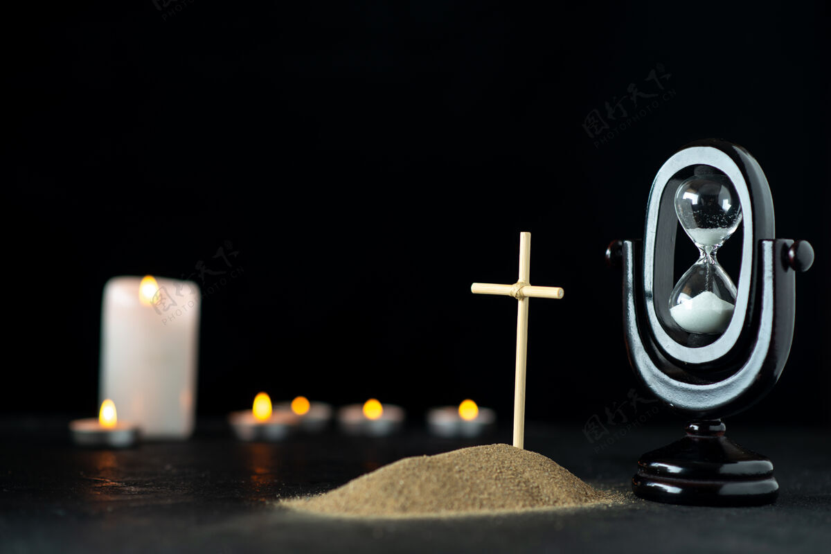 沙漏沙漏和蜡烛黑暗的小坟墓的正面视图光事件旗