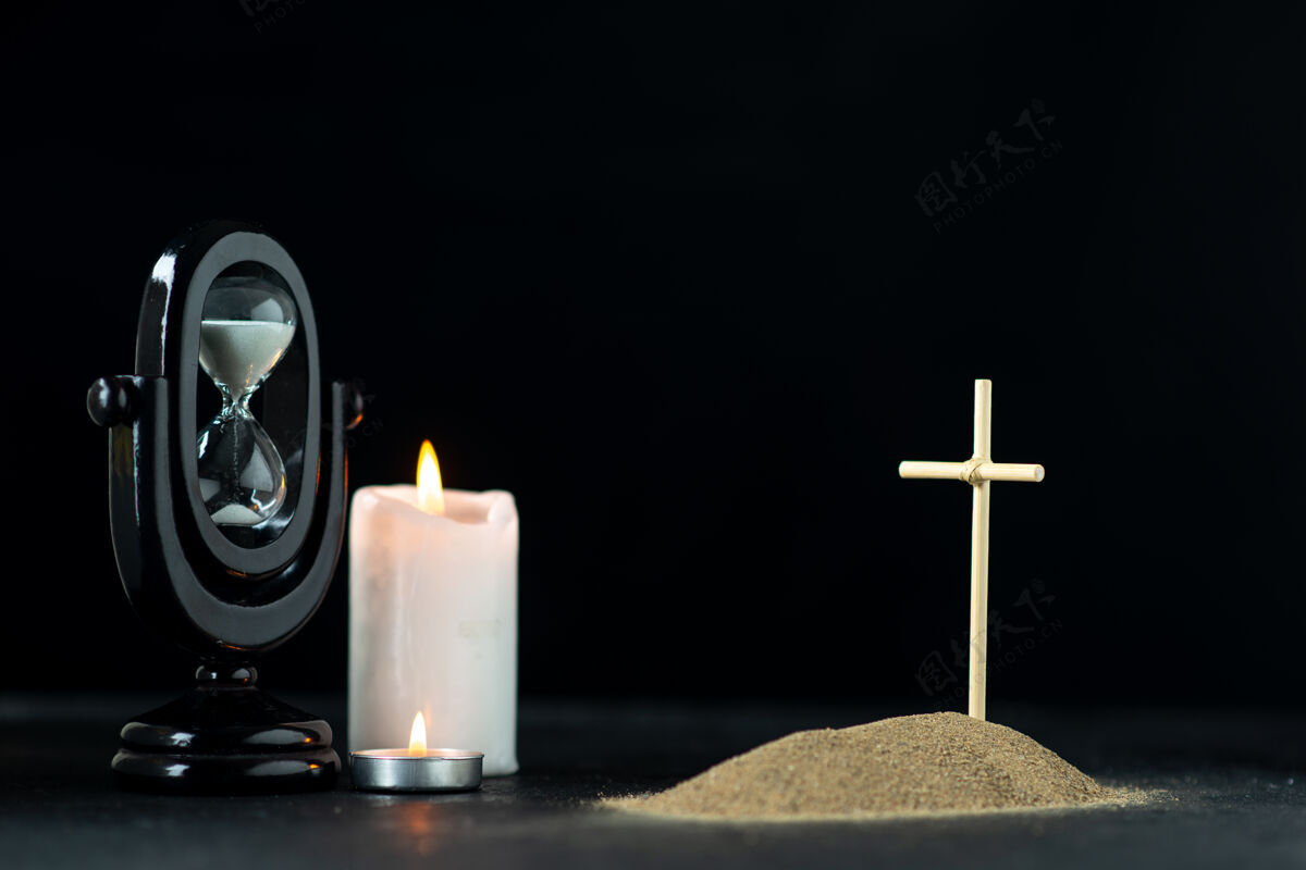 沙漏沙漏和蜡烛黑暗的小坟墓的正面视图打蜡庆典烛光