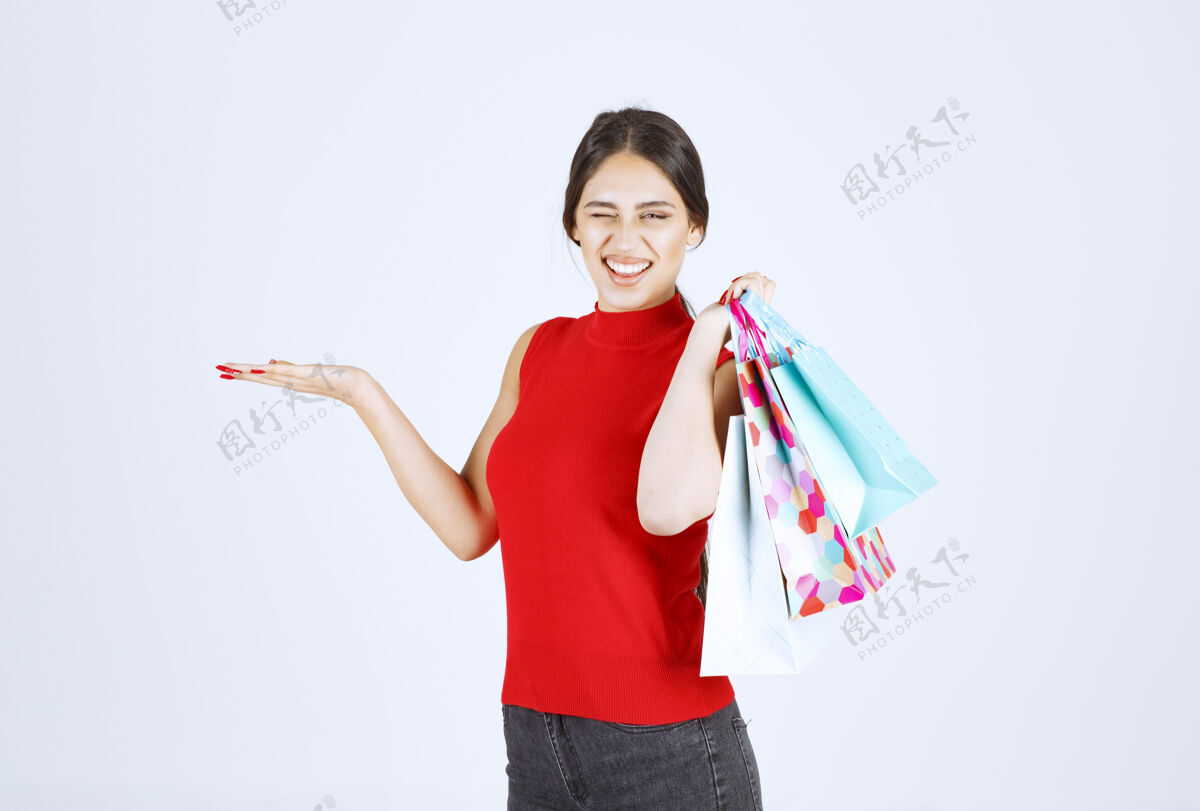 成年人穿红衬衫的女孩肩后背着五颜六色的购物袋姿势工人潮流
