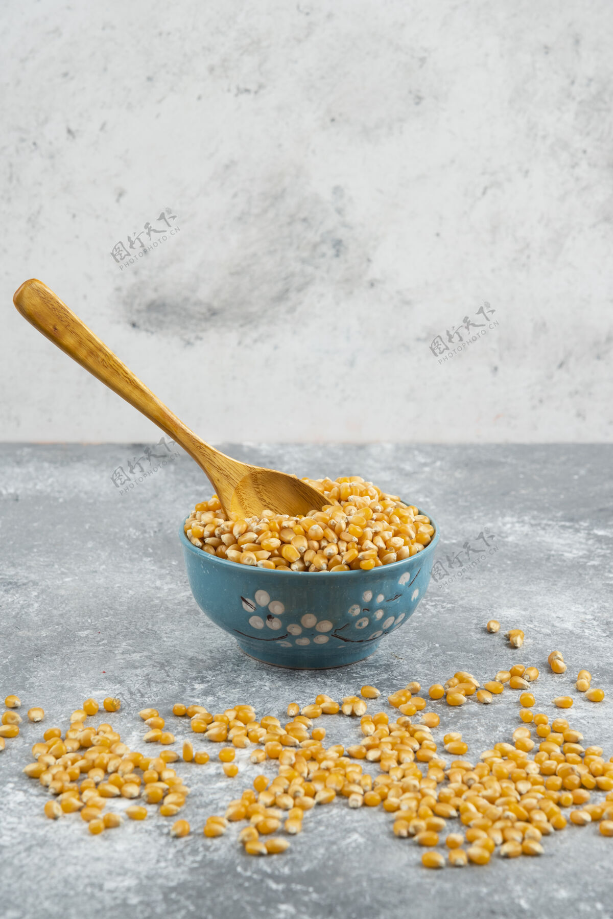 有机用木勺把生玉米粒放在蓝碗里谷类堆玉米