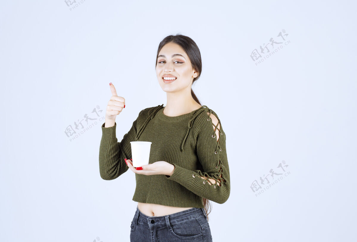 人黑发女人拿着塑料杯竖起大拇指女性年轻杯子