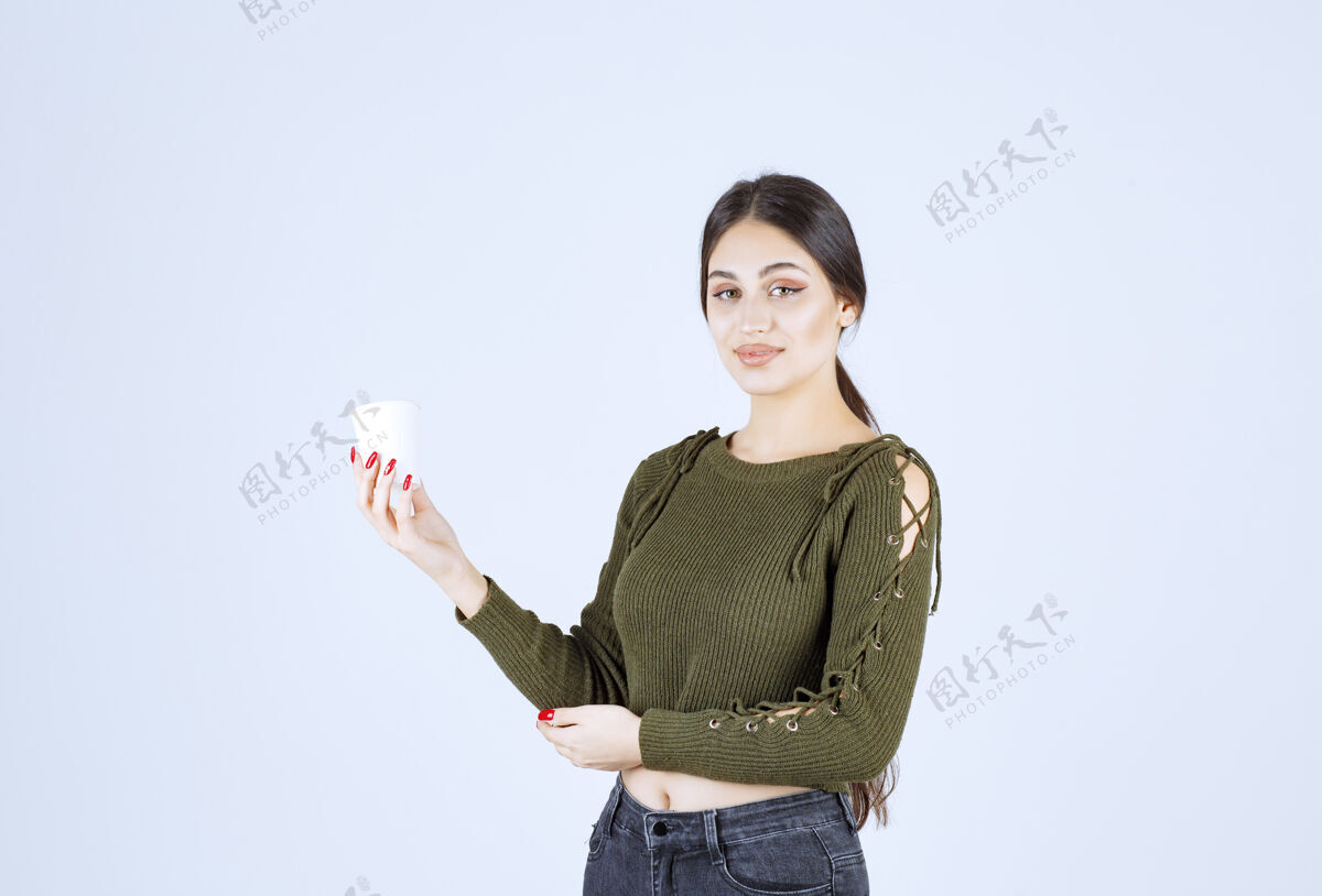 女孩年轻的黑发女人拿着塑料杯摆姿势成人黑发人