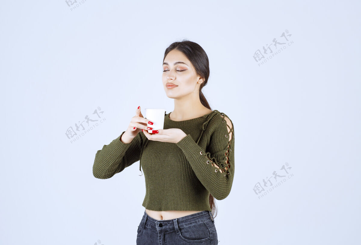 女孩一个年轻漂亮的女模特手里拿着一个装着热饮的塑料杯年轻人类漂亮
