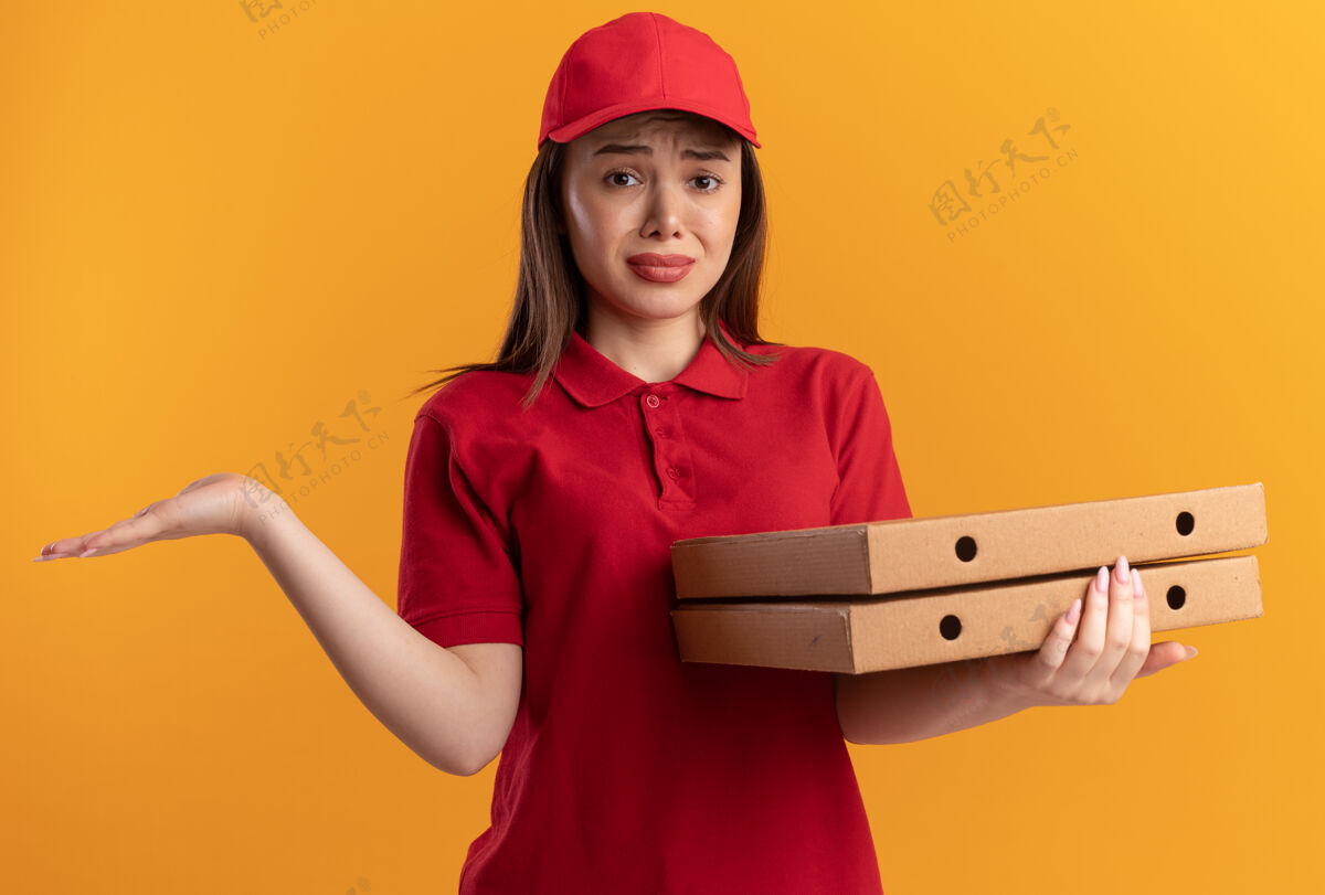 悲伤一个穿着制服的悲伤漂亮的女送货员把手张开 手里拿着比萨饼盒漂亮保持手