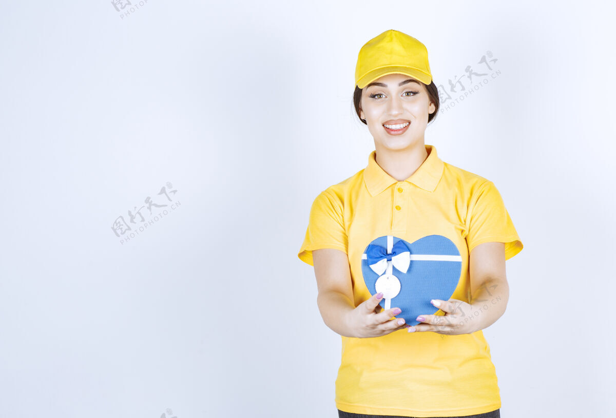 模型一个年轻的女人在白色的墙上放着一个黄色的心形盒子喜欢微笑心