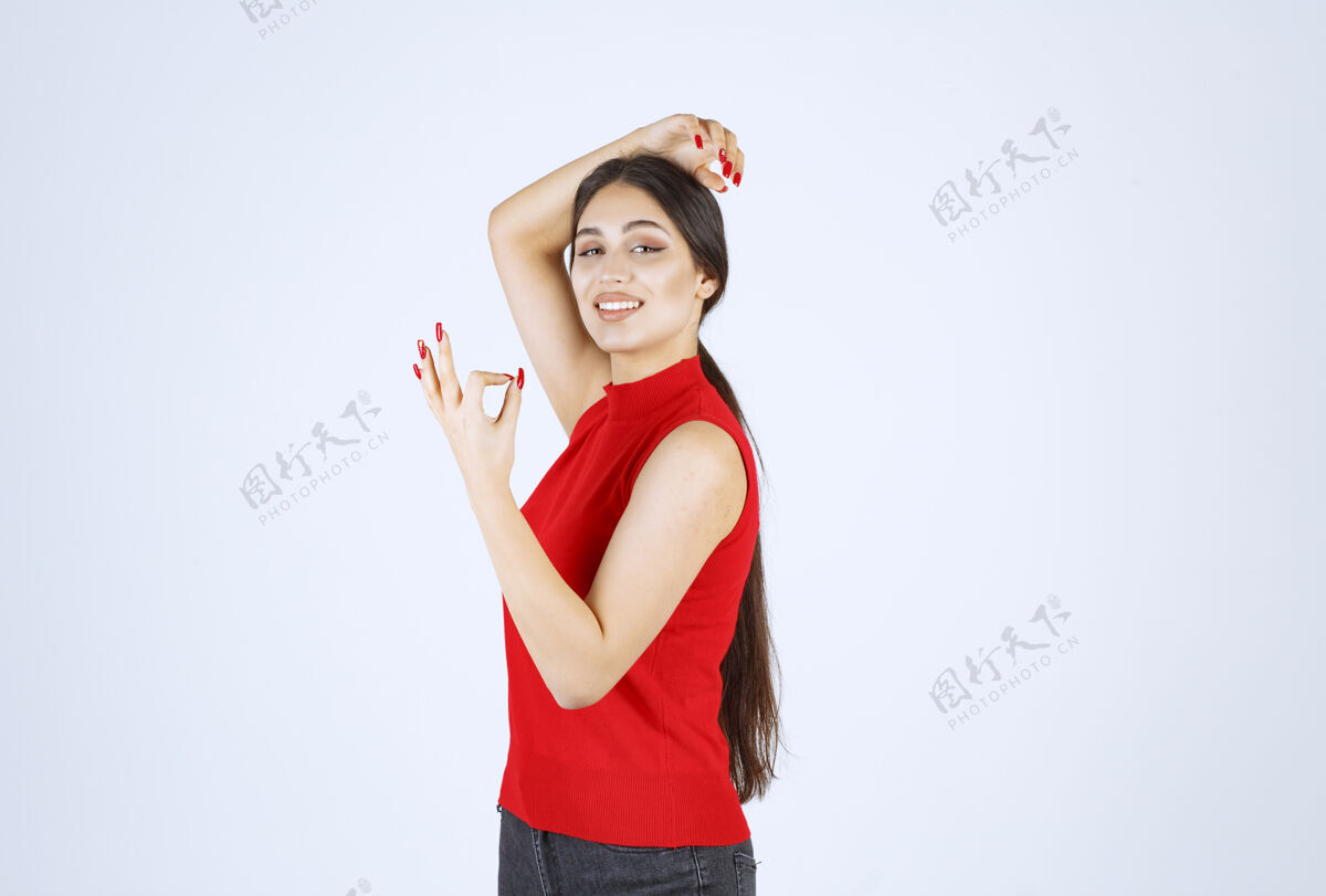 人穿红衬衫的女孩显示出积极的手势满意工人喜欢