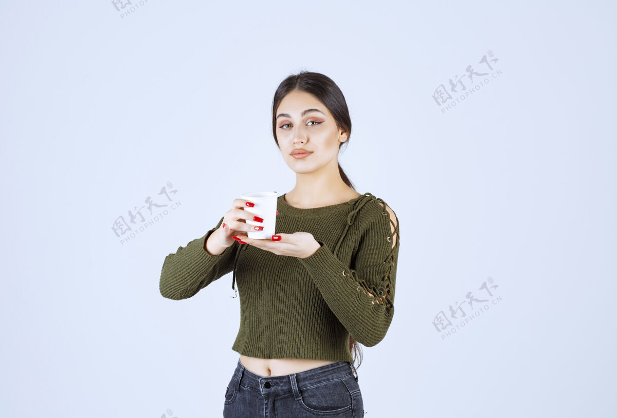 女孩一个年轻漂亮的女模特手里拿着一个装着热饮的塑料杯人类杯子站着