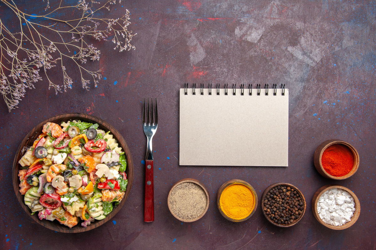 制作俯瞰美味的蔬菜沙拉与不同的调味品在黑暗的背景健康饮食蔬菜沙拉午餐脸粉顶部蔬菜