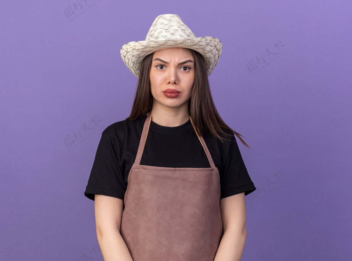 紫色严肃漂亮的白人女园丁戴着园艺帽看着镜头帽子穿女