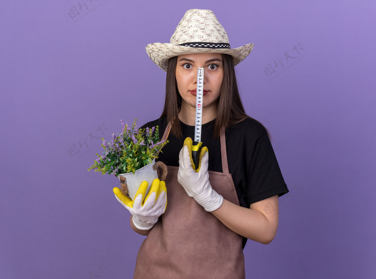 花盆一个漂亮的白人女园丁戴着园艺帽拿着花盆和卷尺测量穿女