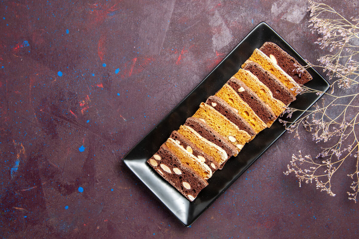 设备俯瞰美味的蛋糕片 蛋糕盘里有坚果 背景是深色的甜茶蛋糕糖饼干饼干甜点茶算盘
