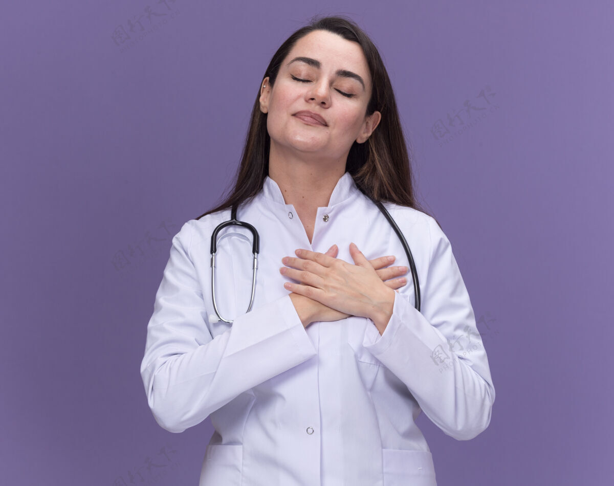 长袍年轻的女医生穿着医用长袍 手持听诊器 双手放在胸口胸部手听诊器