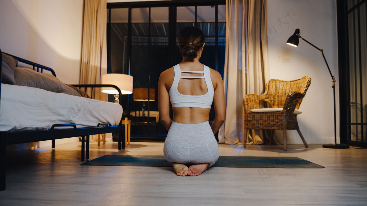 年轻年轻的亚洲女士穿着运动服 晚上在家里的客厅里做瑜伽练习沙发公寓健康