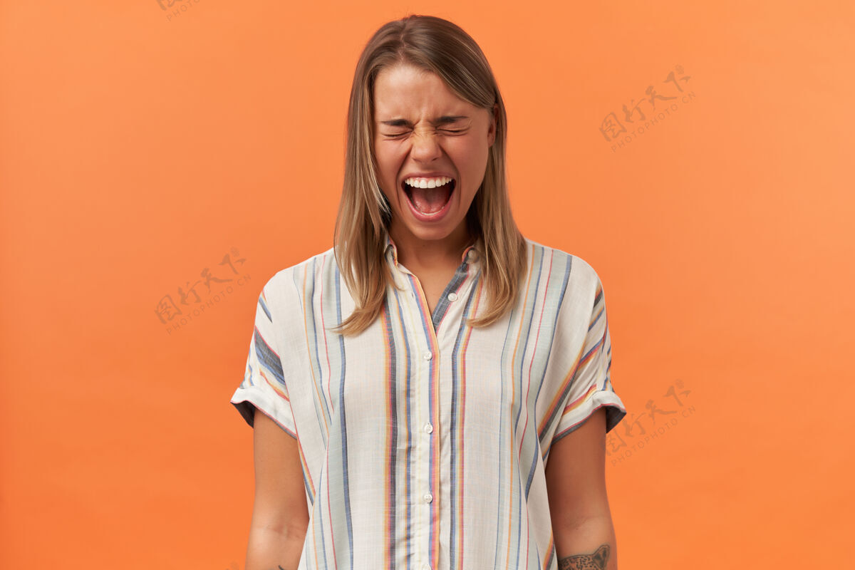 眼睛穿着条纹衬衫的疯疯女人站在橙色的墙上尖叫着情绪条纹肖像