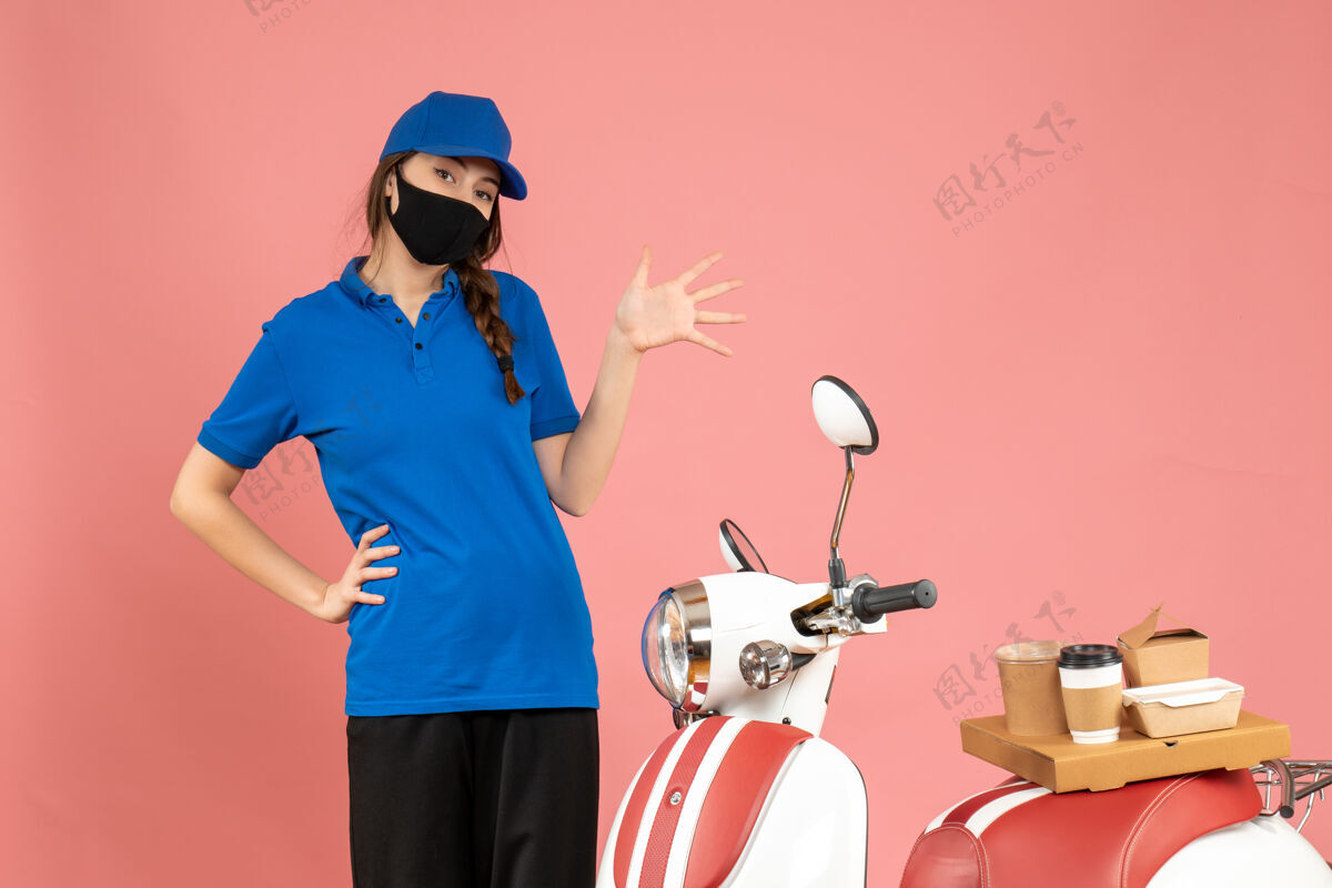 人俯视图：戴着医用面罩的信使女孩站在摩托车旁 粉色背景上有咖啡蛋糕桃商业成人