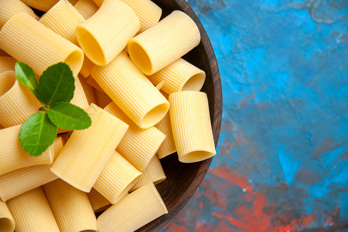 一半准备晚餐的半张照片 蓝色背景的棕色锅里放着绿色的意大利面新鲜度假健康