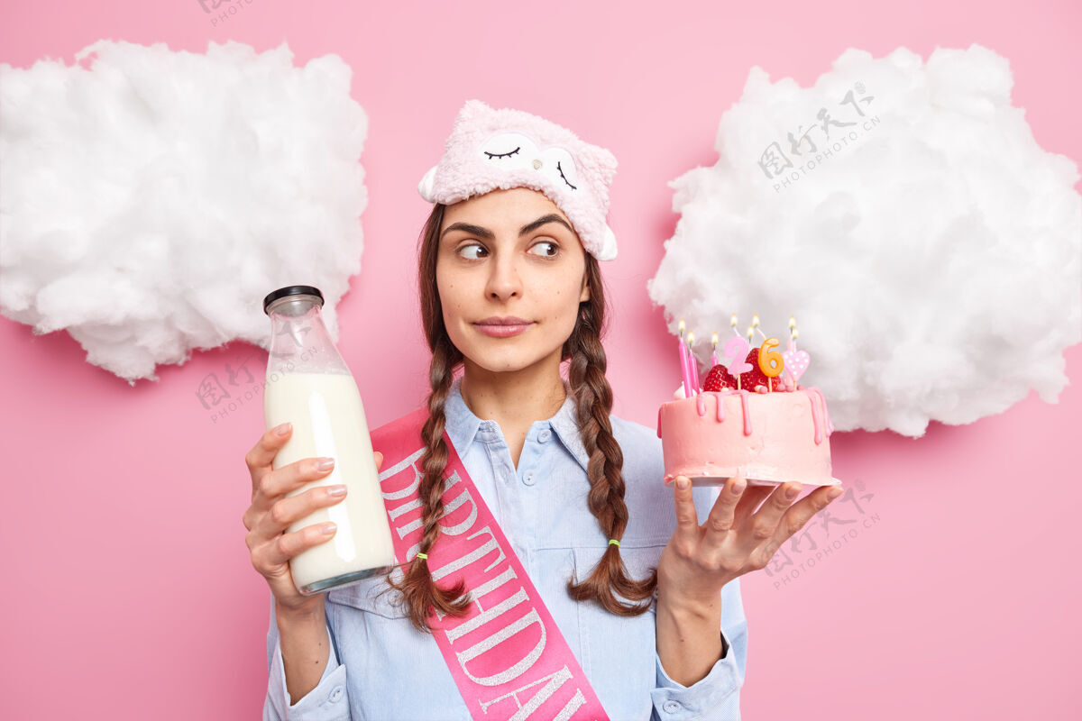 甜点女人聚精会神地站在一边 手里拿着美味的蛋糕和一瓶牛奶 准备在生日那天吃喜宴 穿着粉色的睡衣气球罗茜蛋糕