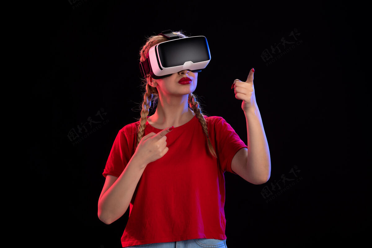 人物年轻女性在黑暗的墙上玩虚拟现实的正面图肖像正面年轻女性