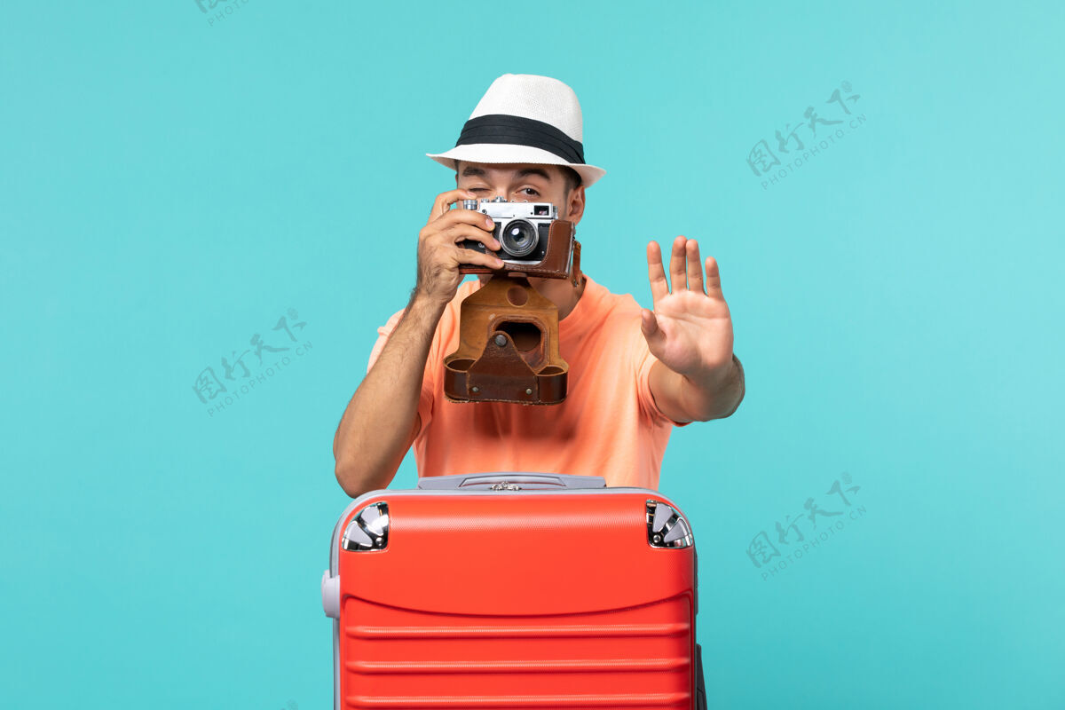 假期带着红色手提箱和蓝色相机拍照的度假男人男性相机人