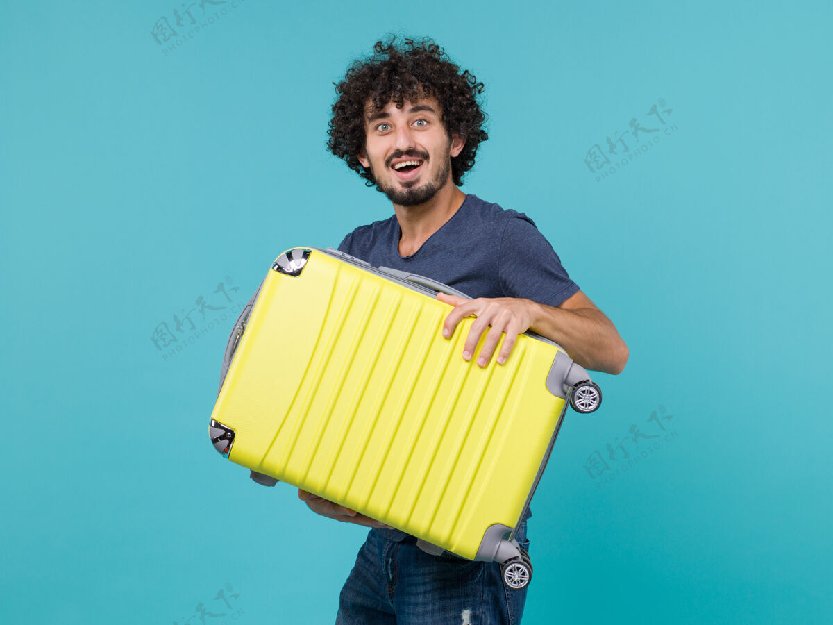 旅行度假的男人拿着蓝色的大黄色手提箱假期男性休闲