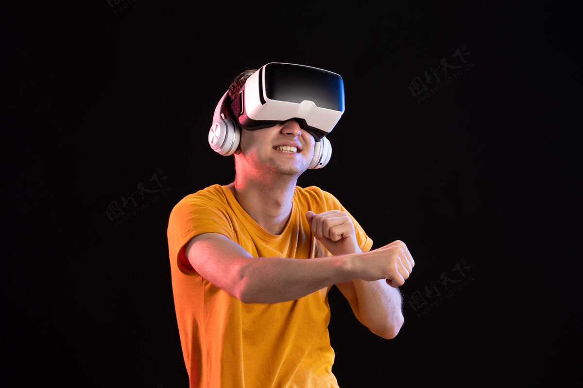 视觉年轻人戴着耳机在黑暗的墙上玩虚拟现实的画像人耳机视觉