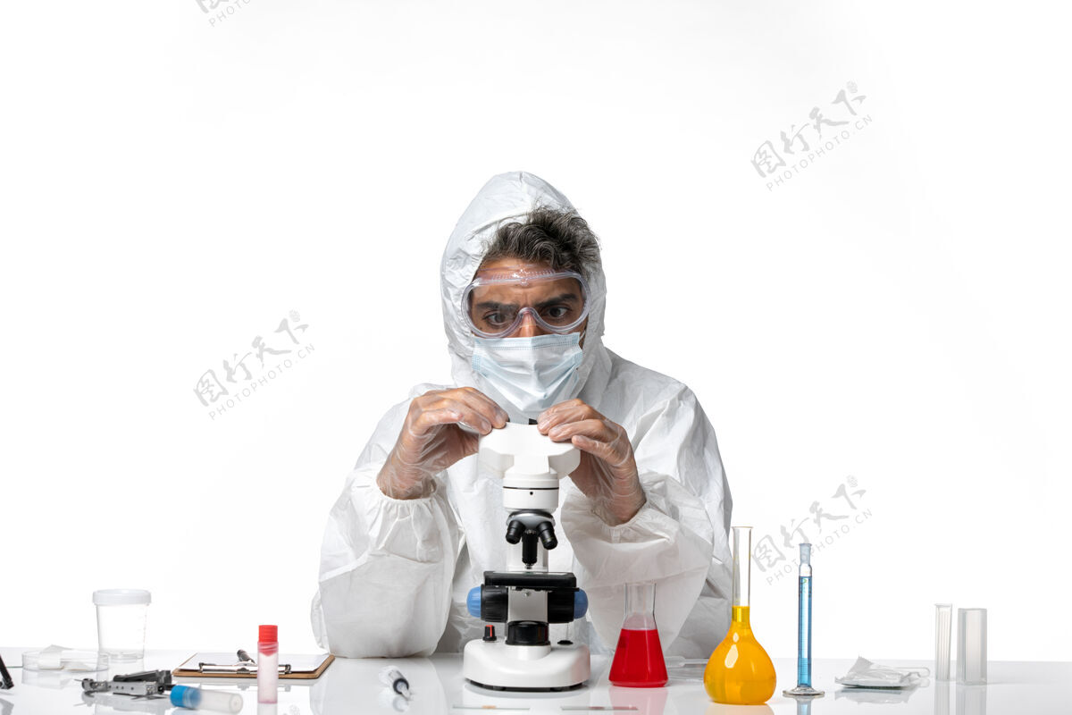 专业男医生穿着防护服 戴着口罩 用显微镜对着白色套装口罩防护