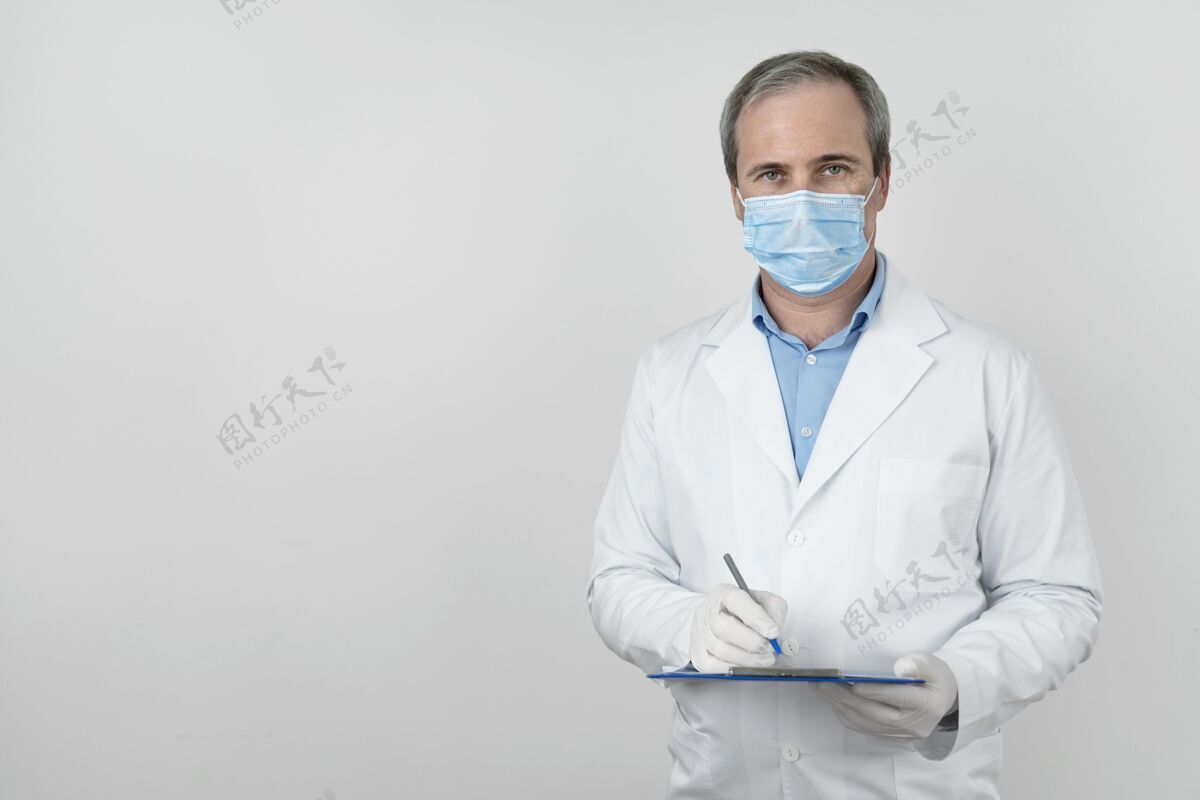 男性男性医生的前视图 带着医用面罩和记事本 为患者接种疫苗做准备医生乳胶手套复制空间