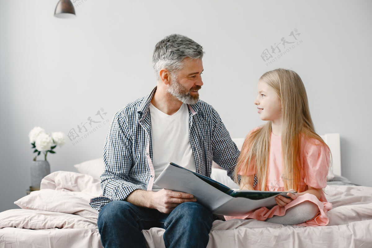 孙子为人父母可爱的女孩和爷爷坐在卧室里一起看书年龄未成年关系