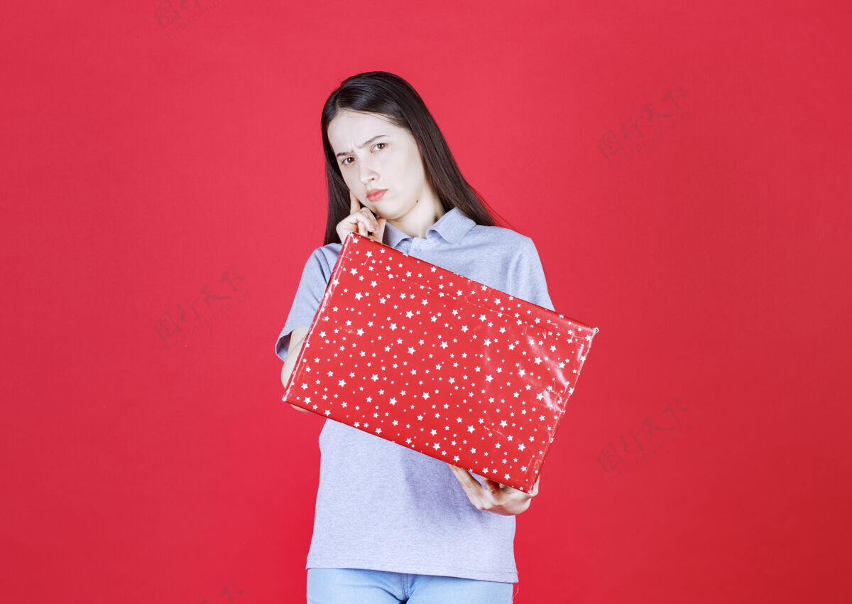 礼物恼火的女人拿着礼品盒看着相机购物微笑玩耍