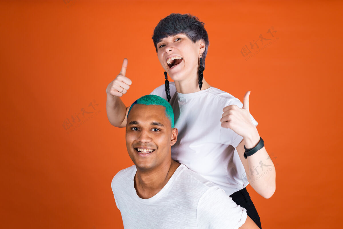 约会年轻男女在随意的白色橙色墙上快乐和积极的情绪显示拇指向上美丽积极成人