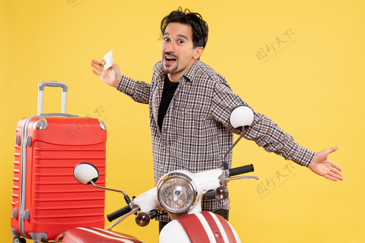 周围正面图年轻男子骑着自行车 手持飞机票 在黄色背景的公路上旅行 度假 骑摩托车旅行骑马音乐家吉他