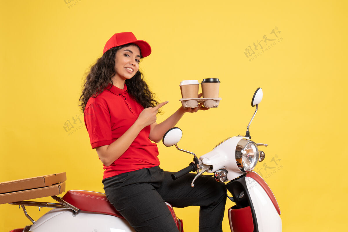 制服正面图骑自行车的女快递员拿着咖啡杯在黄色背景上工作服工作服女快递员工作自行车成人工作