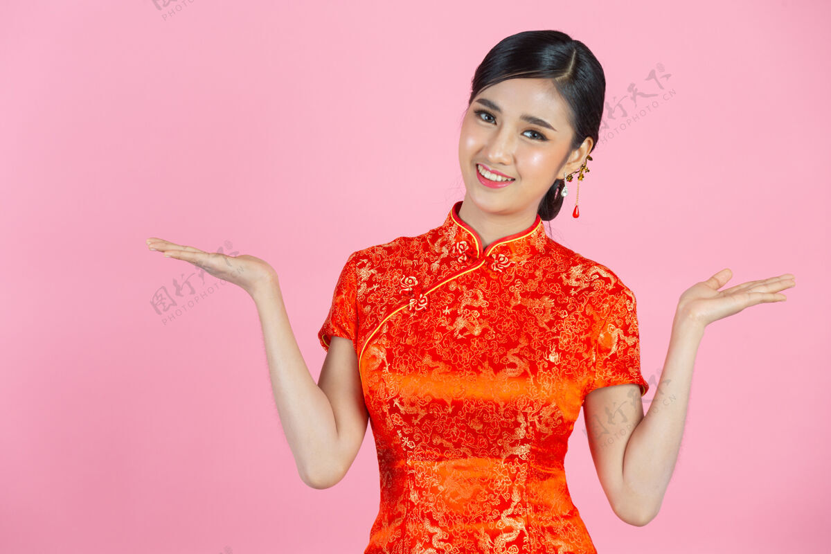 年美丽的亚洲女人快乐的微笑 在中国新年的粉红色背景上向你展示一些东西欢呼东方人展示