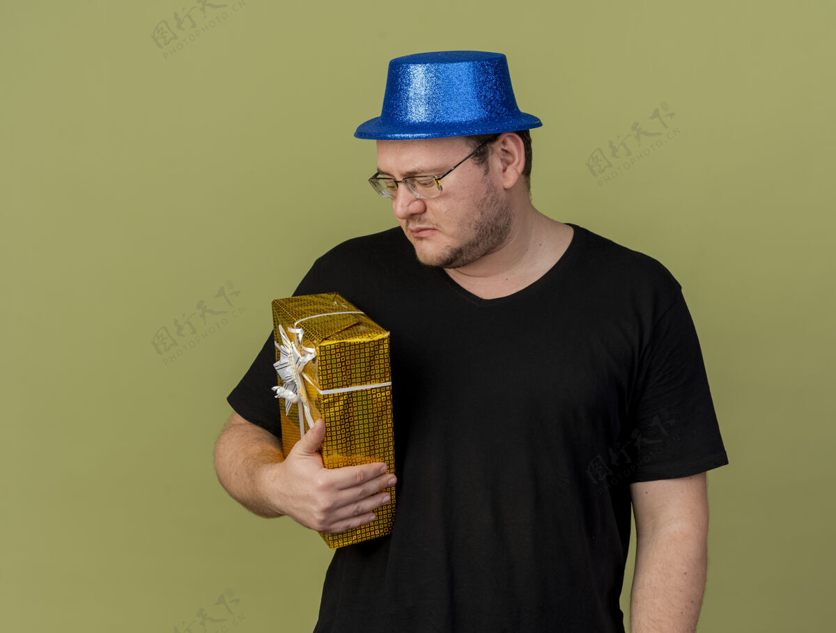 斯拉夫失望的成年斯拉夫人戴着眼镜 戴着蓝色派对帽 拿着礼物盒看帽子穿光学