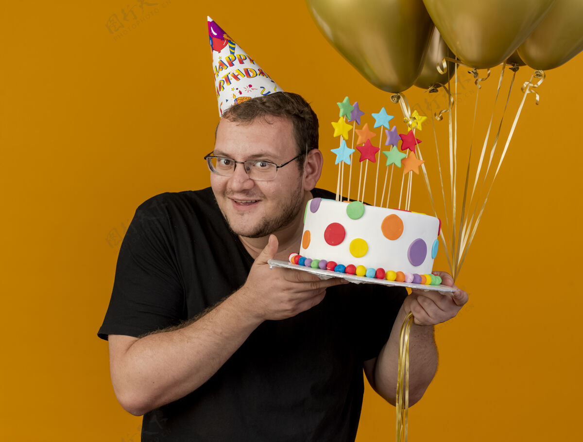 成人高兴的成年斯拉夫人戴着眼镜 戴着生日帽 手里拿着氦气球和生日蛋糕斯拉夫眼镜帽子