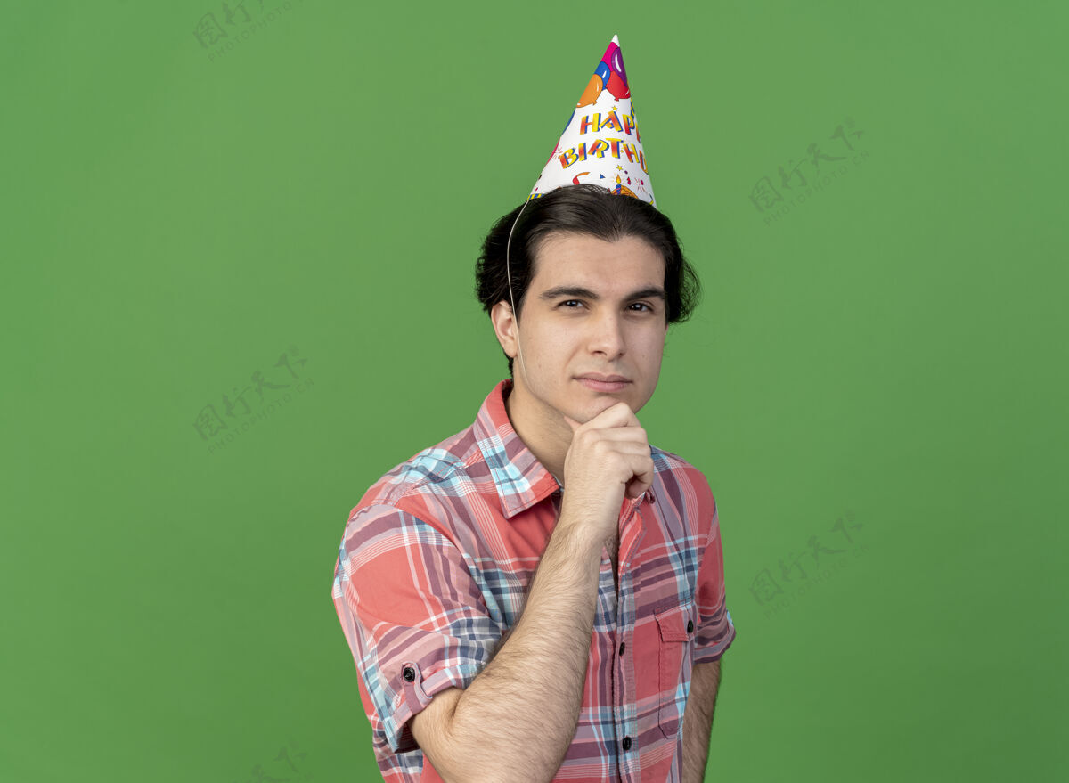举行体贴英俊的高加索男子戴着生日帽托着下巴生日空间英俊