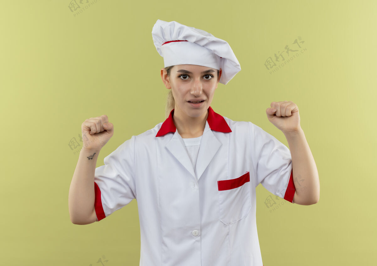 拳头年轻漂亮的厨师穿着厨师制服 举起拳头孤立在绿墙上漂亮烹饪印象