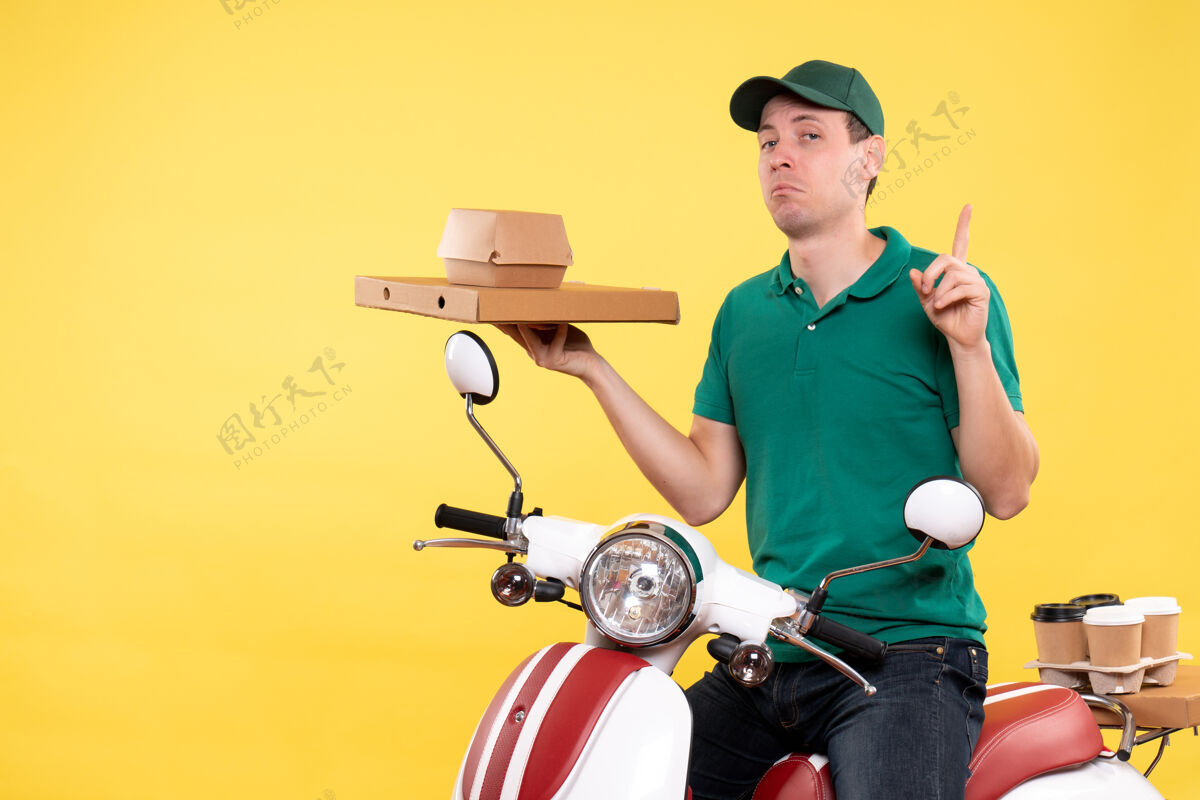 工作正面图身着制服的年轻男快递员拿着黄色的食品包装制服年轻男性信使货箱