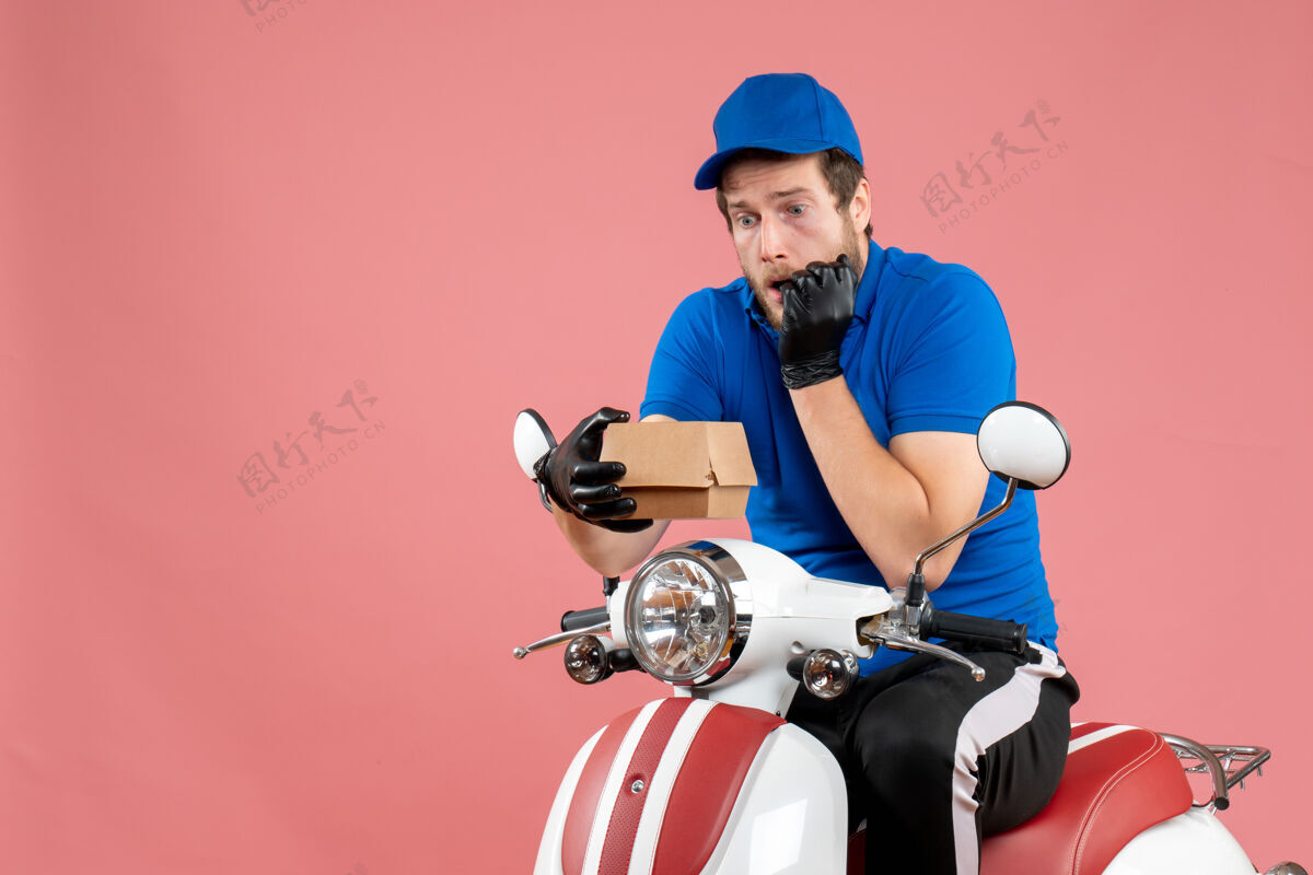 工人正面图男性信使坐在自行车上 拿着粉红色的小食品包抱着工作工作