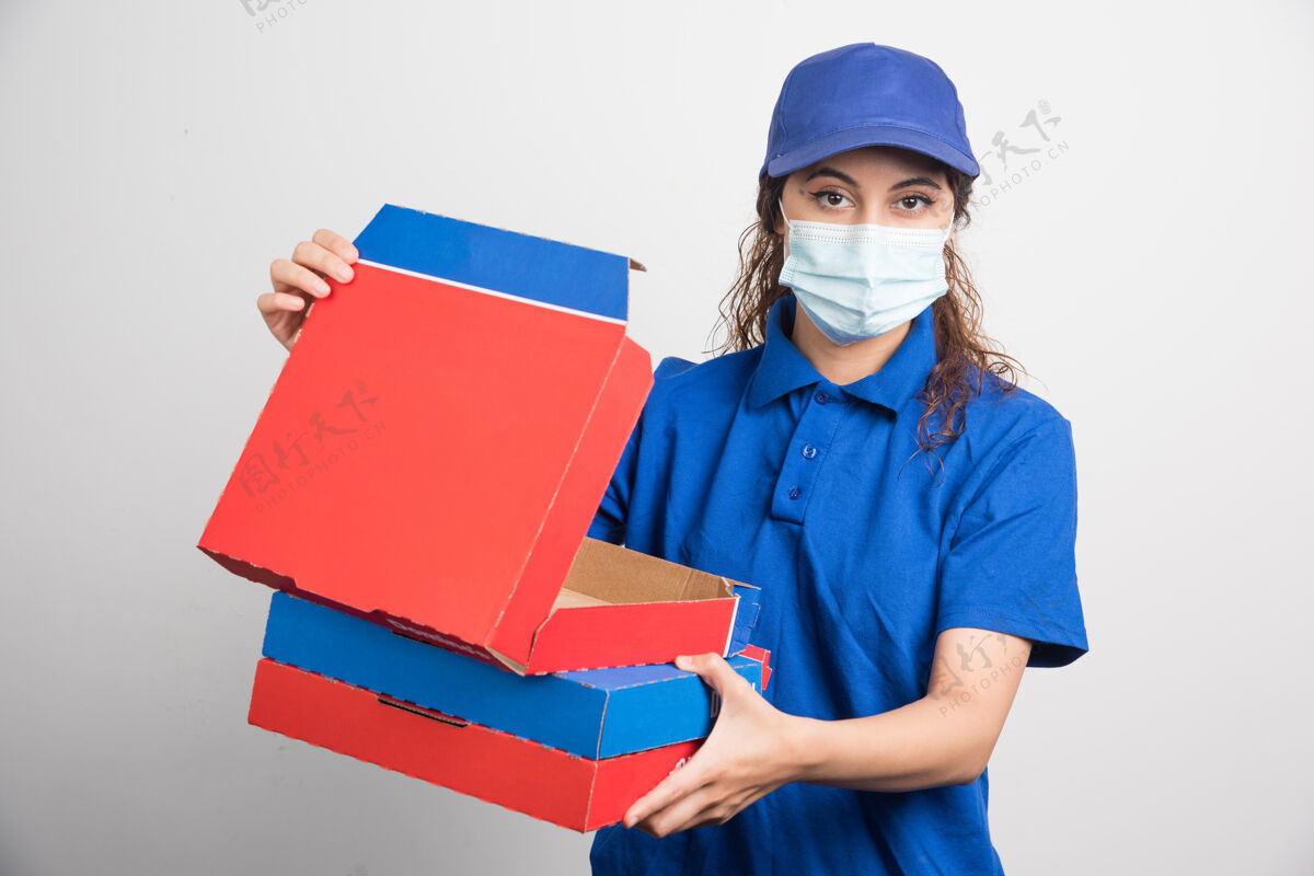 用餐披萨送货员打开其中一盒披萨 上面有白色的医用面膜工人面罩快递