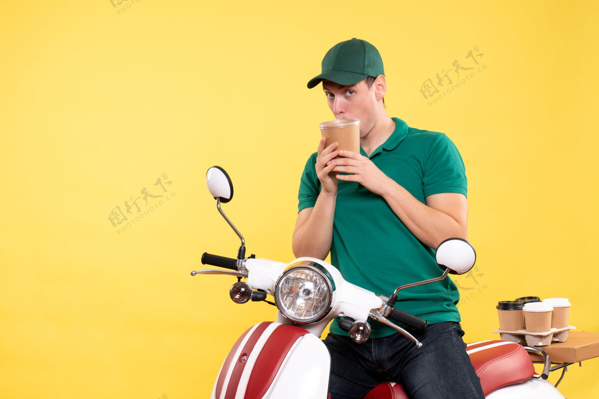 摩托车正面图身着制服的男信使手里拿着一个黄色的咖啡杯车辆制服自行车