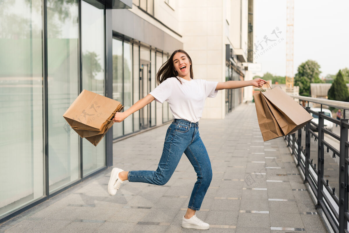 女人快乐的美女手里拿着五颜六色的购物袋 欢快地在空中跳跃时尚消费主义成人