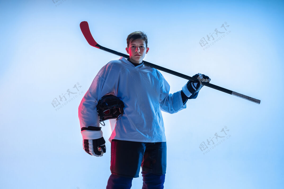 复制空间年轻的男性冰球运动员在霓虹灯下用棍子粘在白墙上专业运动服冷
