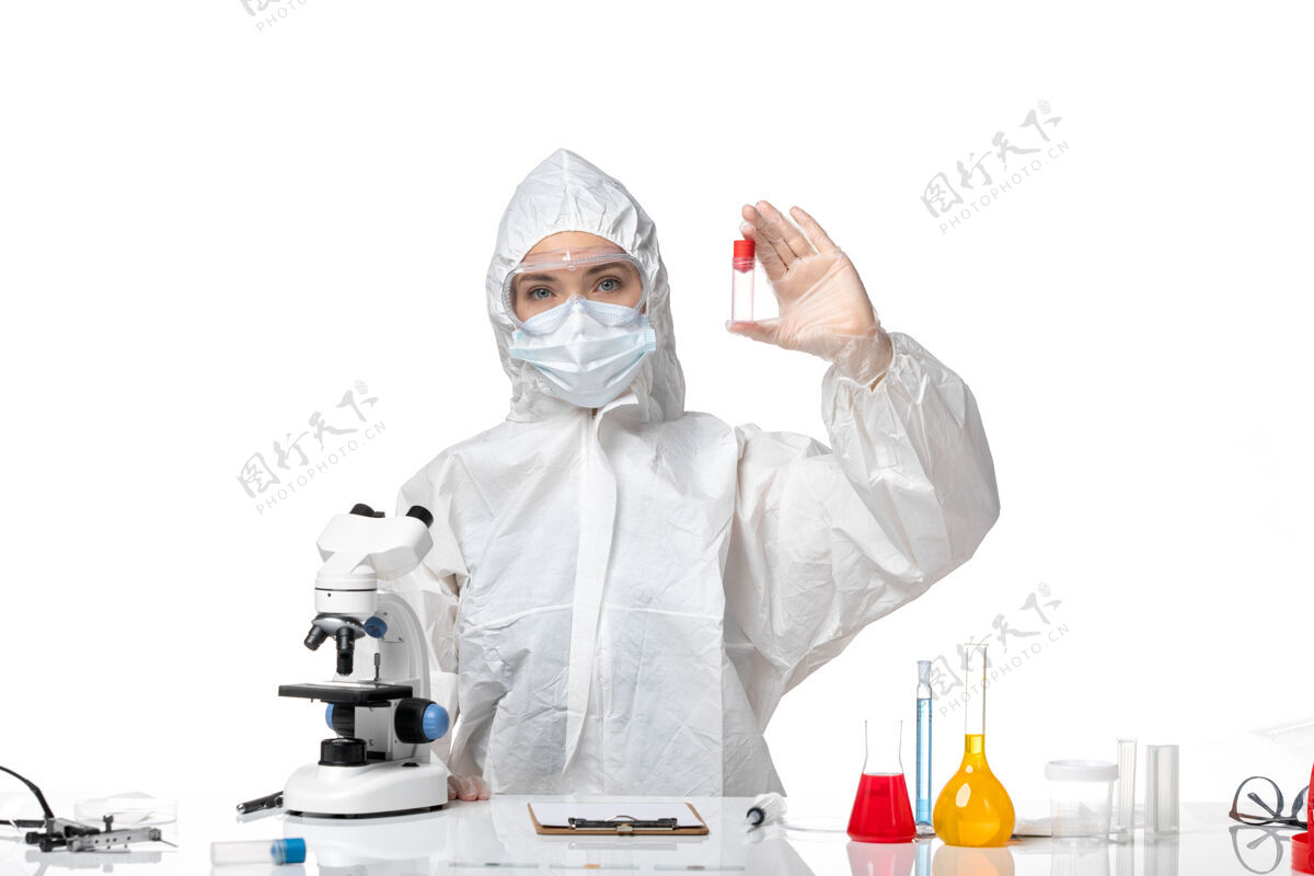 大流行正面图年轻女医生穿着白色防护服 戴着口罩 由于白色背景上有柯维德手持烧瓶大流行 飞溅病毒健康柯维德-防护实验室外套套装