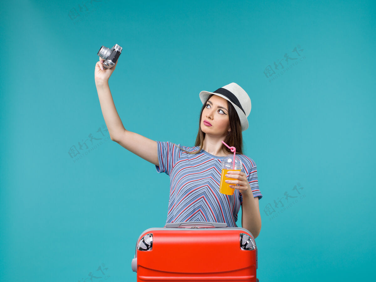 果汁前景度假妇女手持果汁和相机在蓝色背景下航行暑假海上旅行旅程举行肖像