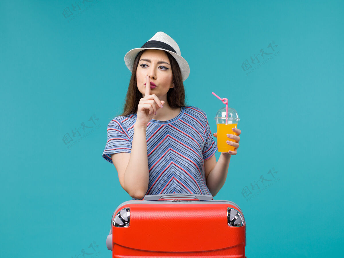 女性前视图度假妇女与她的红色袋子举行了浅蓝色的背景旅行度假女性果汁旅行包微笑