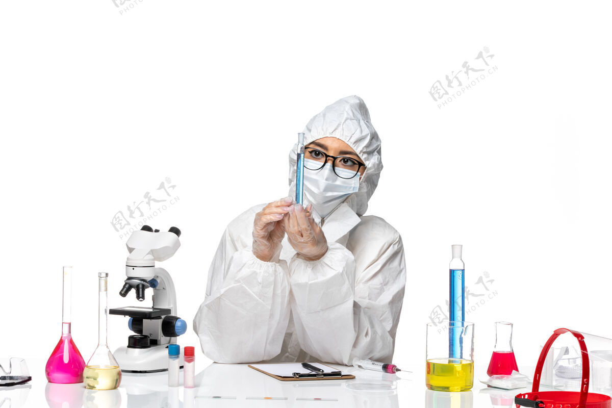 实验室正面图身穿特殊防护服的年轻女化学家手持白色背景蓝色溶液烧瓶-化学病毒实验室溶液化学套装