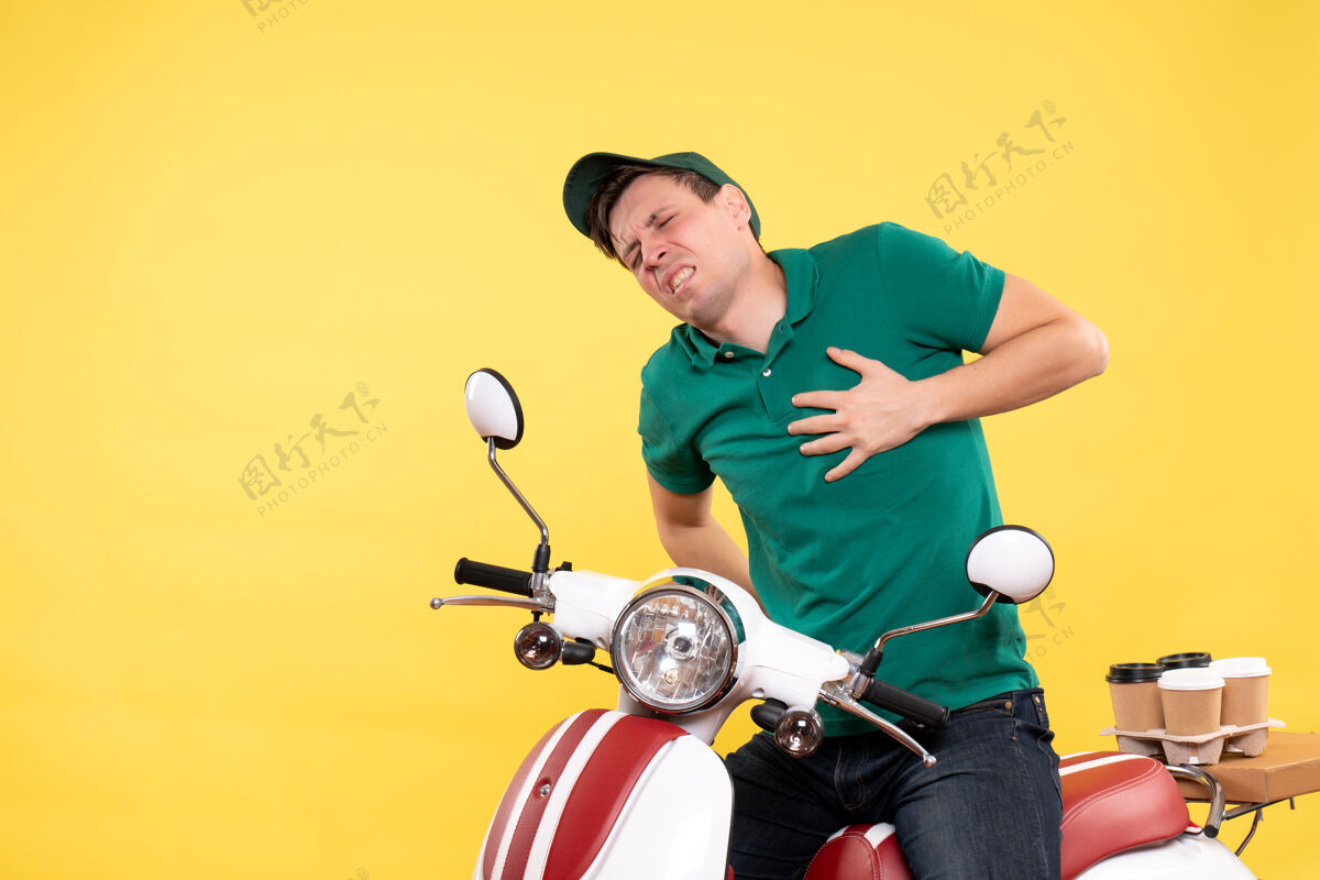 自行车正面图身着绿色制服骑自行车的年轻男信使有心痛的黄色摩托车人年轻男性信使